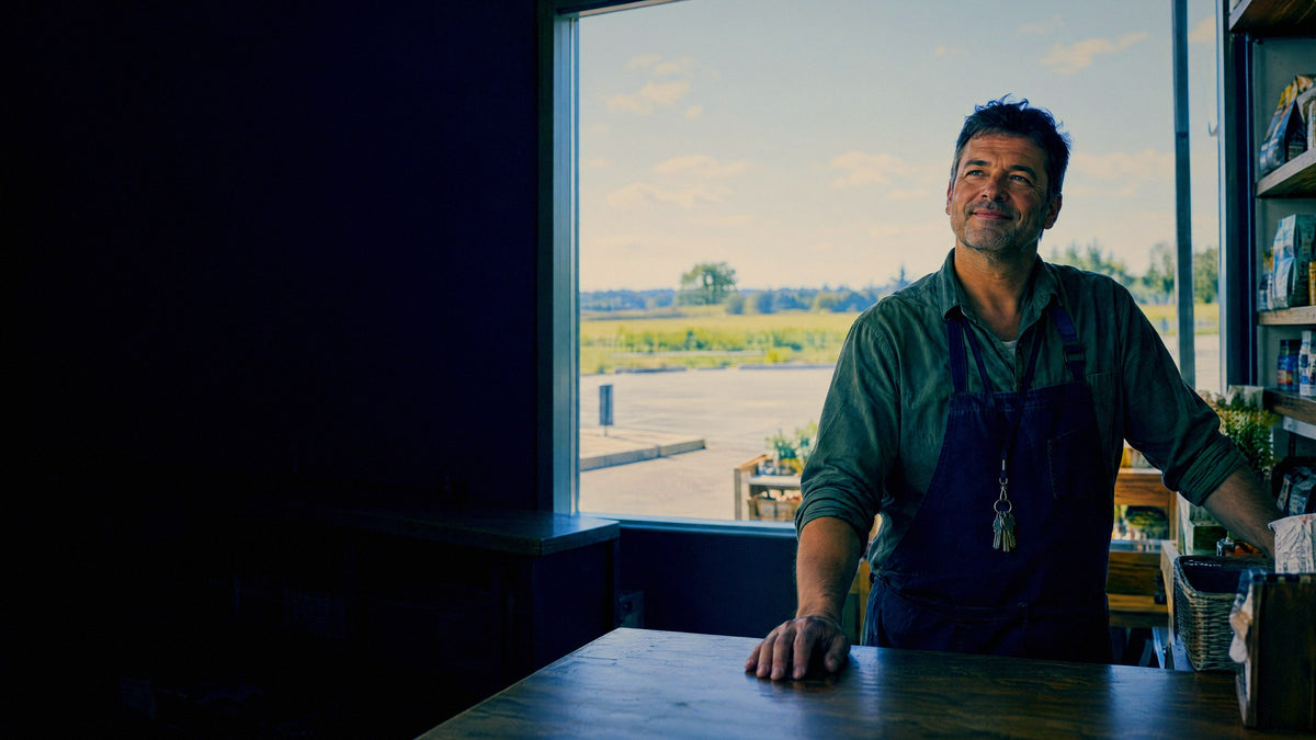The owner of a small independent store stands behind his own counter as a customer comes in