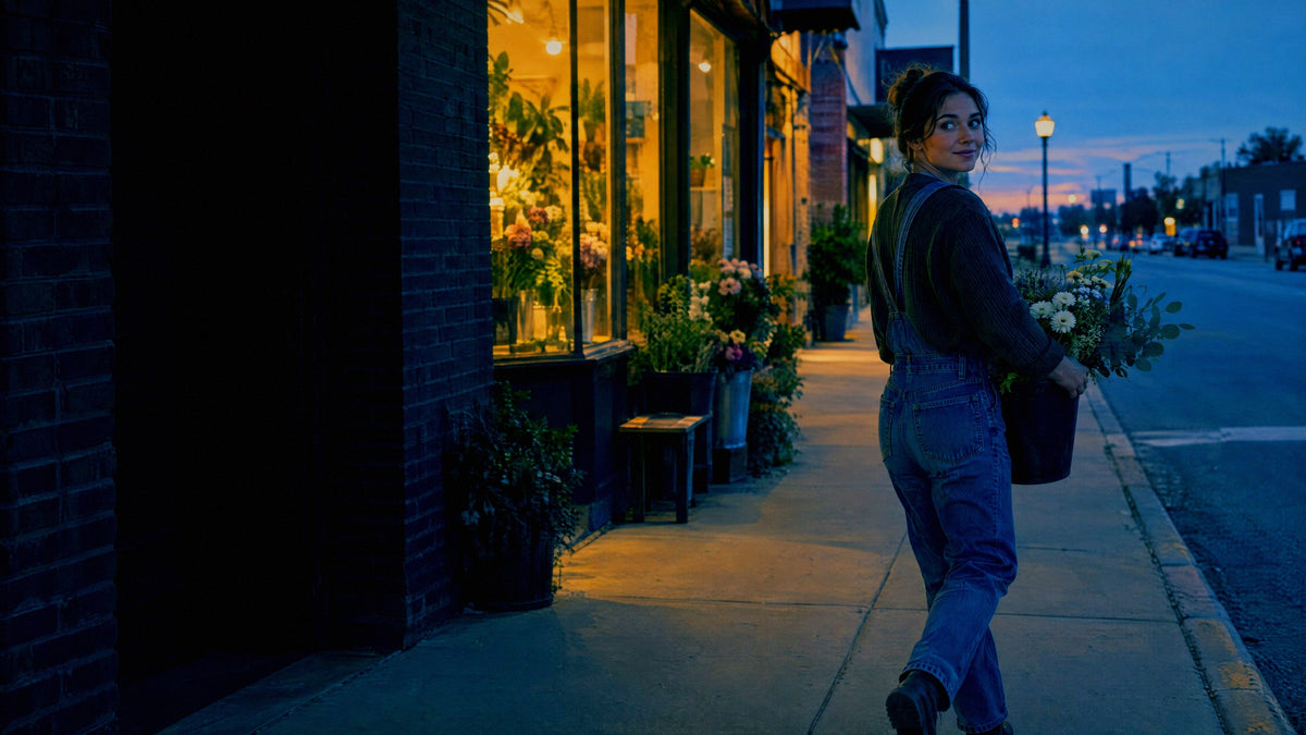 A florist carries a bucket of stems into her main street shop as the last blue light leaves the sky
